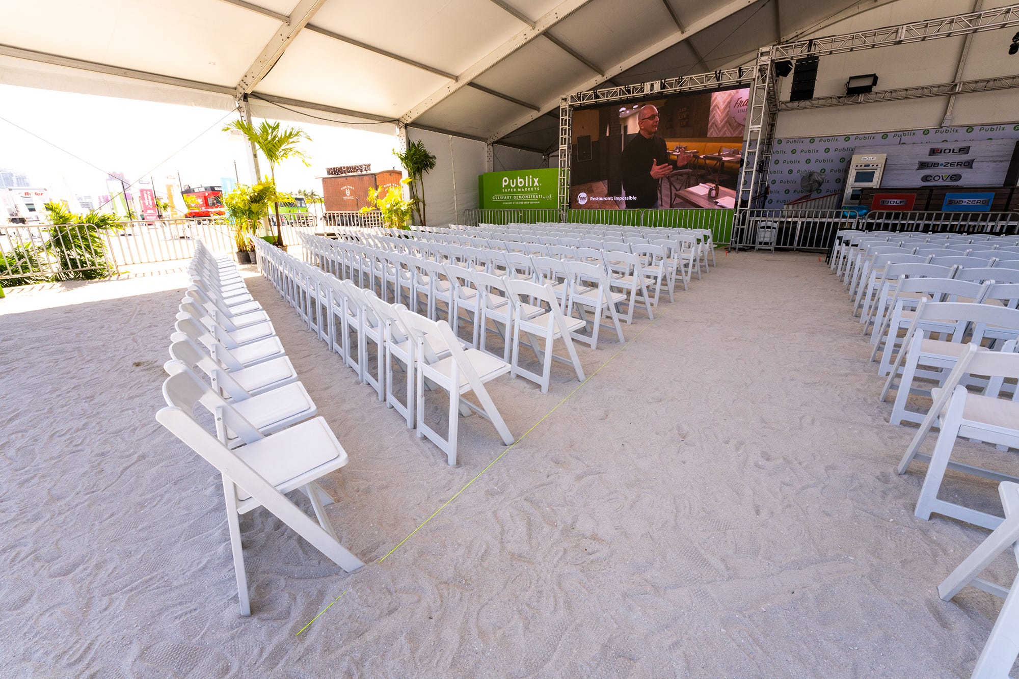 white folding chairs set up near a stage for a beach event