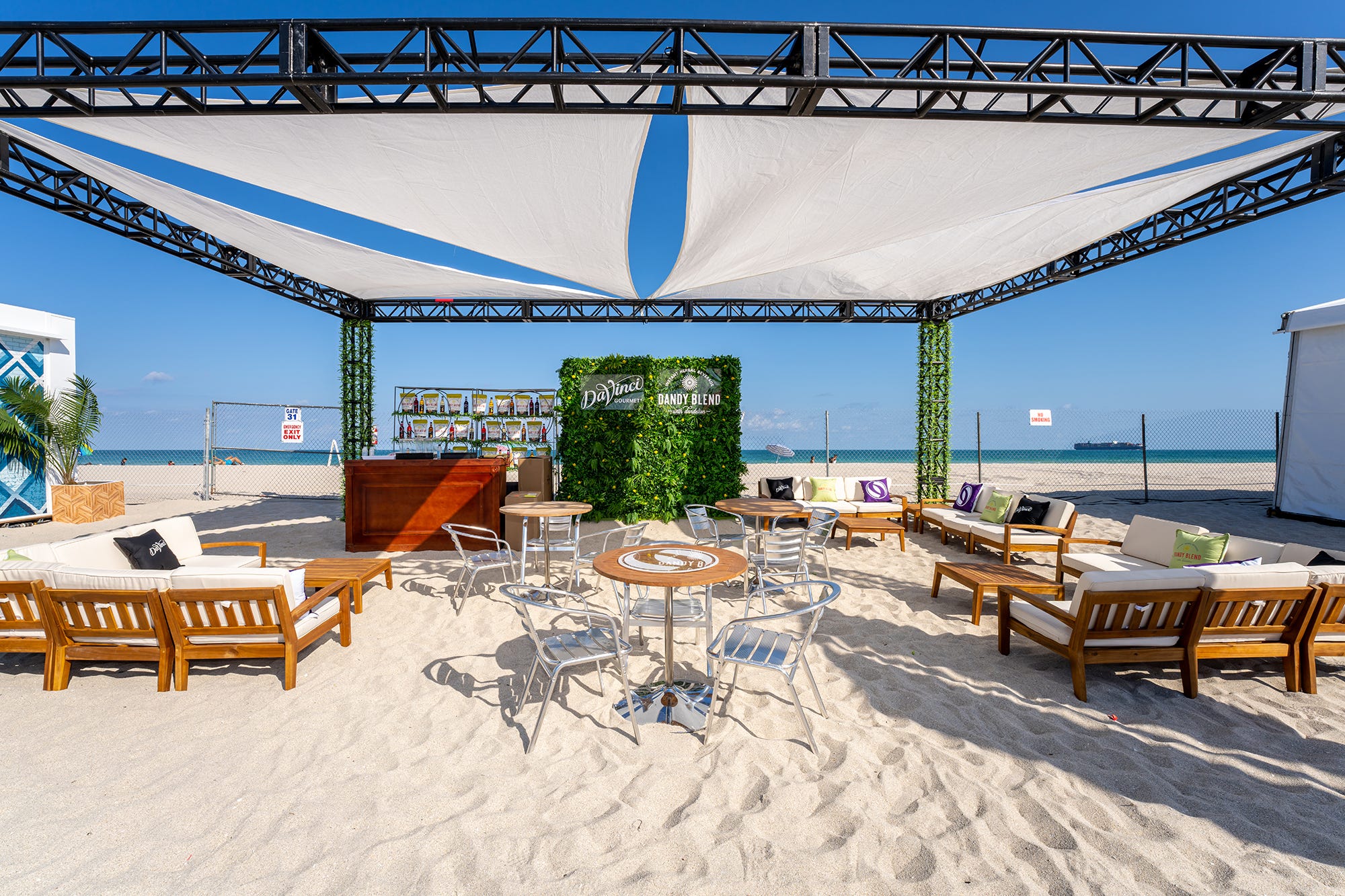 outdoor event on the beach featuring outdoor sofas, sectionals, chairs and tables near a stage